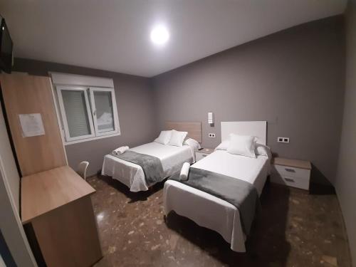 a hotel room with two beds and two windows at AYAMONTE ROOMS 43 in Ayamonte