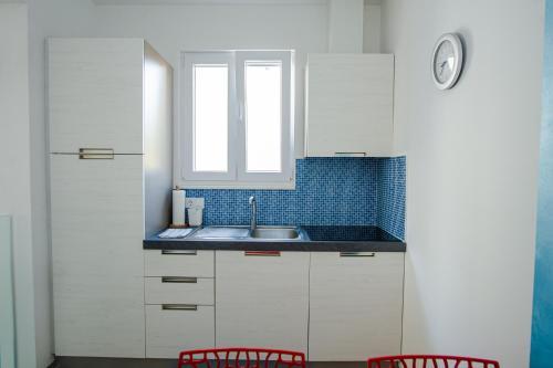 a kitchen with white cabinets and a sink and two red chairs at Exclusive Seaside Dream Apartments in Murter