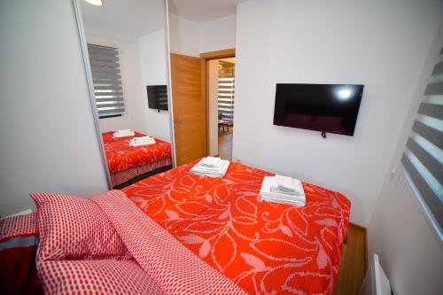 a bedroom with a red bed and a mirror at Apartment Center Valley in Vila Pekovic Green in Zlatibor