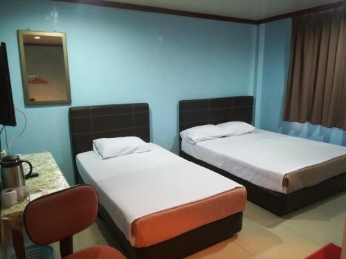 um quarto com duas camas, uma mesa e uma cadeira em MIRAMAR HOTEL em Sibu