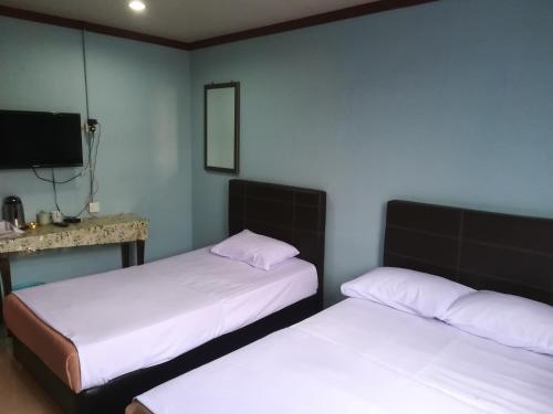 Cette chambre dispose de 2 lits et d'une télévision murale. dans l'établissement MIRAMAR HOTEL, à Sibu