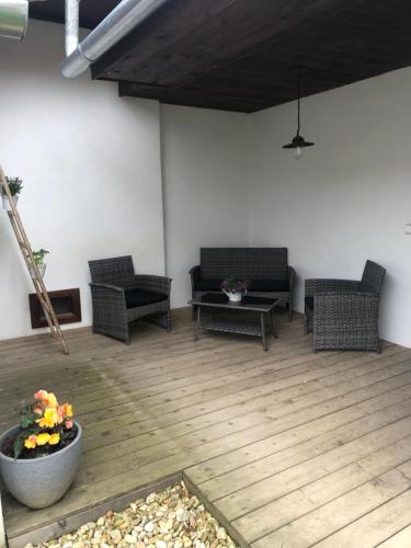 a patio with wicker chairs and a table on a wooden floor at Sonnenhof in Limbach im Burgenland