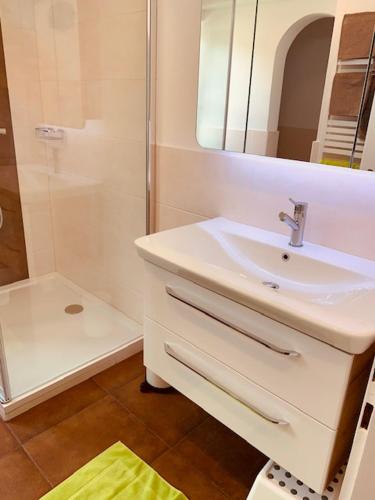 a white bathroom with a sink and a shower at Apartementhaus Schöndorfer in Strobl