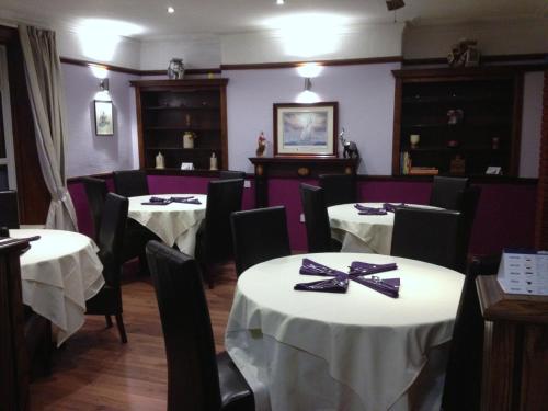 uma sala de jantar com mesas brancas e cadeiras pretas em Croxdale Inn em Durham