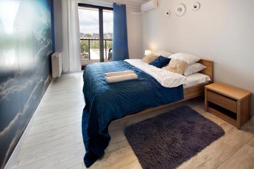 ワルシャワにあるP&O Business Serviced Apartments CYBERNETYKIのベッドルーム1室(青い毛布、窓付)