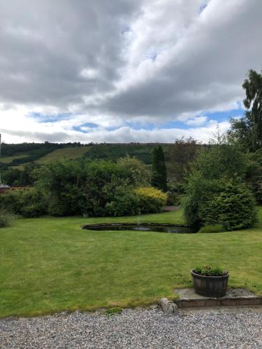 a garden with a large yard with a flower pot at Kilmore Farmhouse in Drumnadrochit