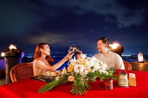 a man and woman sitting at a table with a flower arrangement at Munduk Heaven Luxury Villas in Munduk