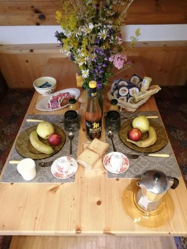 a table with plates of food and a vase of flowers at B&B PRA' DEI CERVI in Telve