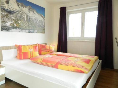 ein Schlafzimmer mit einem weißen Bett und bunten Kissen in der Unterkunft Haus 4 Holidays in Bramberg am Wildkogel