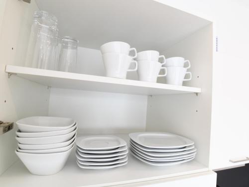 a white cabinet with plates and cups and bowls at WESTSIDE Hotel in Munich