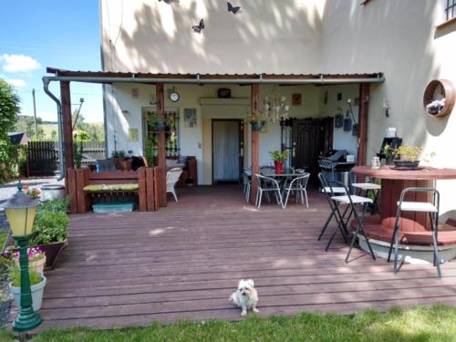 a dog sitting on a wooden deck in front of a house at Pension Novy Den in Albrechtice
