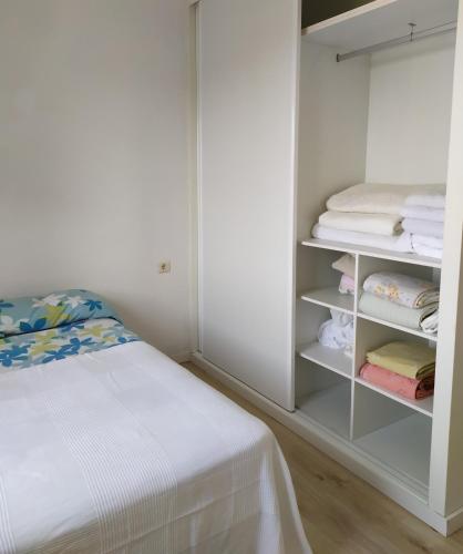 a bedroom with a bed and a closet with towels at Living Pontevedra in Pontevedra