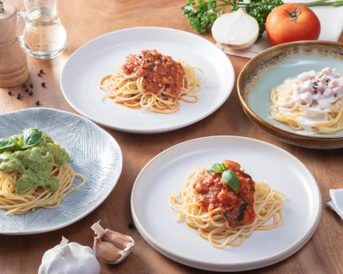a table topped with plates of pasta and sauce at Ravin Home ราวินโฮม in Nakhon Nayok