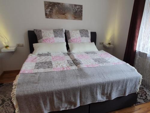 a bed with a pink and gray quilt on it at Ferienwohnung Hitz in Hinterzarten