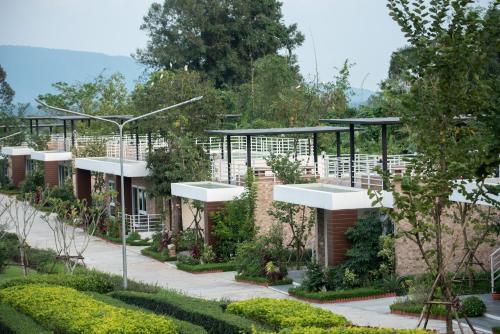 a row of buildings in a garden with trees at Ravin Home ราวินโฮม in Nakhon Nayok