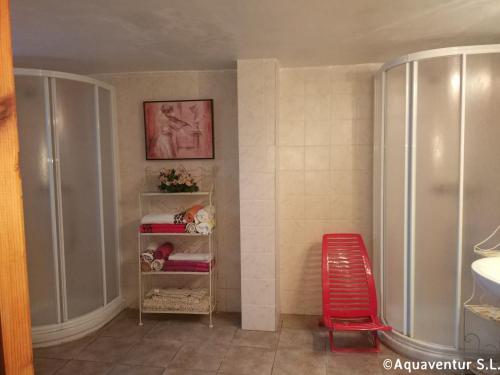 a bathroom with a shower and a red chair at Casa de los piragüistas in Taravilla