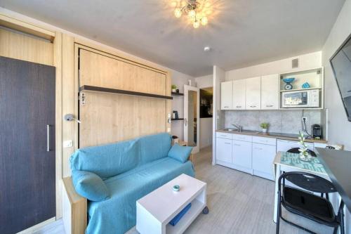 un salon avec un canapé bleu et une cuisine dans l'établissement Blue Beach vue Mer Clim Wifi, à Roquebrune-Cap-Martin