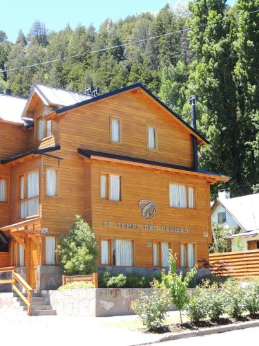 a large wooden building with a sign on it at Apart Hotel Le Temps Des Cerises in San Martín de los Andes