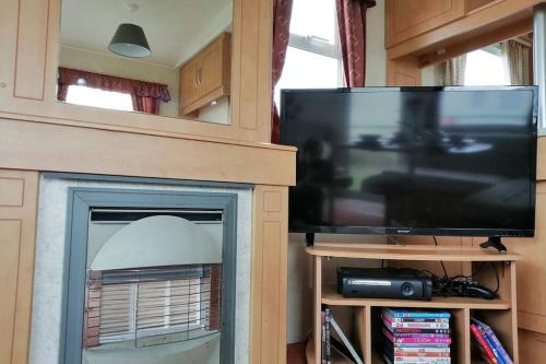 a living room with a fireplace with a flat screen tv at Beachside, Family-friendly, WiFi, 8 berth Caravan 133 in Skegness