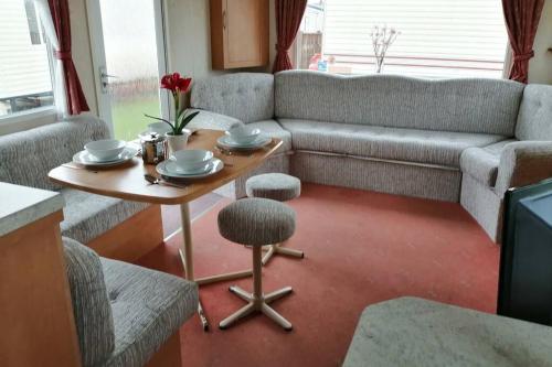 a living room with a table and a couch at Beachside, Family-friendly, WiFi, 8 berth Caravan 133 in Skegness