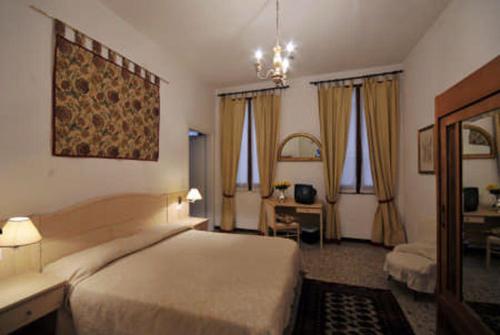 a hotel room with a bed and a desk and windows at Ca' Turelli in Venice