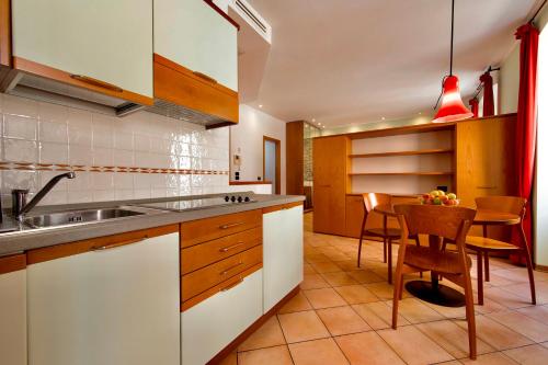 a kitchen with white cabinets and a table with chairs at Residence San Giusto in Trieste