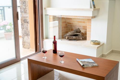 two glasses of wine on a table with a fireplace at Dictamus Homes in Magoulás