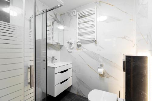 a white bathroom with a toilet and a sink at Apartamenty pod Modrzewiem in Ustronie Morskie