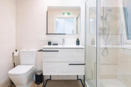 La salle de bains blanche est pourvue d'une douche et de toilettes. dans l'établissement La casa de la abuela, à Olite