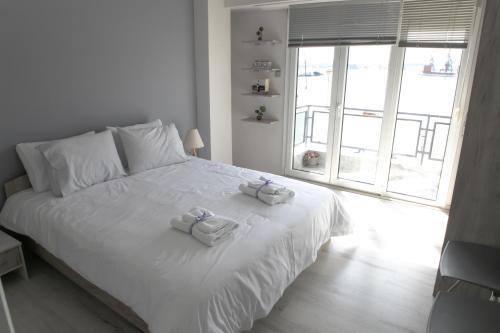 Volos Port View Apartment في فولوس: غرفة نوم بسرير ابيض عليها مناشف
