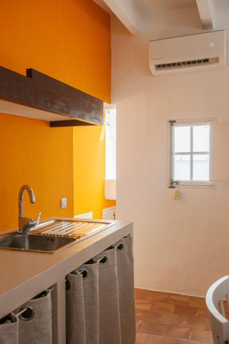 a kitchen with orange walls and a sink at 971 Hotel Con Encanto in Ciutadella