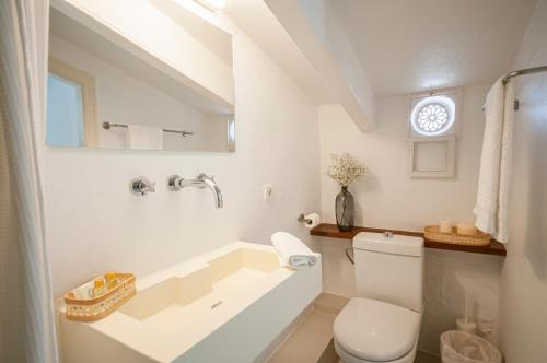 a white bathroom with a tub and a toilet at 971 Hotel Con Encanto in Ciutadella
