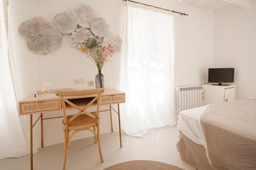 - une chambre avec un bureau et un vase de fleurs sur le mur dans l'établissement 971 Hotel Con Encanto, à Ciutadella
