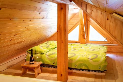 a bed in a wooden room with a bottle of wine at Chalet Letnik in Žiri