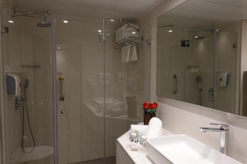 uma casa de banho com um chuveiro, um lavatório e um espelho. em Plaza Nazareth Illit Hotel em Nazaré