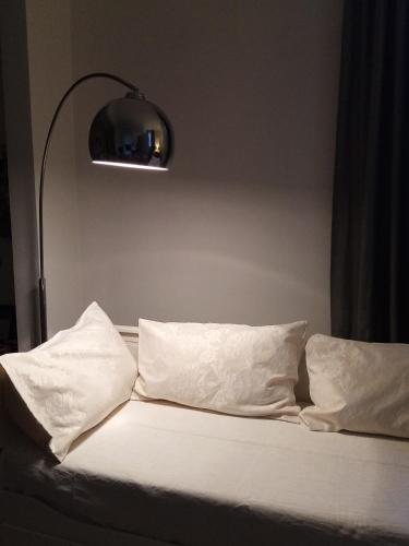 a bed with white sheets and pillows and a lamp at B&B Marana 14 Casa di Campagna in Bologna