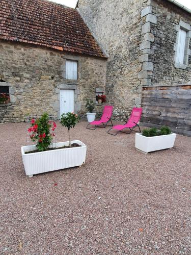 three pink chairs and plants in front of a building at Cottage 2 personnes in Lormes