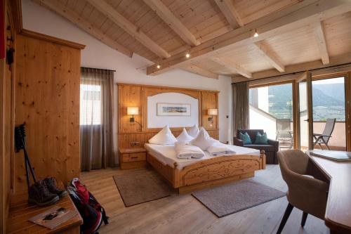 a hotel room with a bed and a desk and a room at Hotel Patriarch in Tirolo