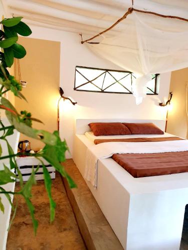 a bedroom with a white bed and a plant at Michamvi Spirit Lodge in Michamvi