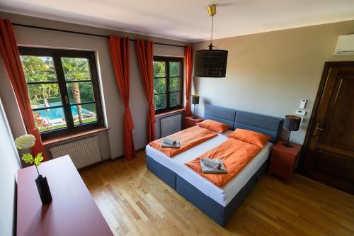 una camera da letto con letto, lenzuola arancioni e finestre di Doppelhaus Villa Casa Alpe Adria a Gradisca dʼIsonzo