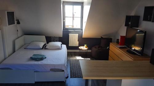 une petite chambre avec un lit et une télévision dans l'établissement QUARTIER HISTORIQUE Studio tout confort, à Blois
