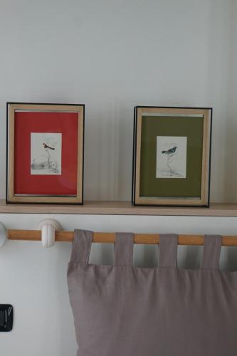 two framed pictures on a shelf above a bed at La Rotonda 2 Camere con terrazza in centro in Pavia