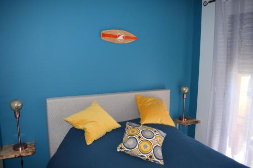 a blue bedroom with a bed with yellow pillows at CB HOME in Audenge