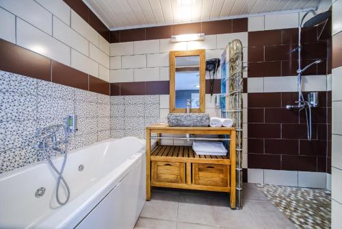 a bathroom with a tub and a sink and a mirror at Sud Hôtel in Le Tampon