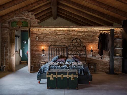 1 dormitorio con 1 cama grande en una pared de ladrillo en Cascina Facelli - Luxury Country House, en Bossolasco