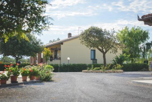 a house with flowers in pots on a driveway at Agriturismo Corte degli Angeli in Marina di Grosseto