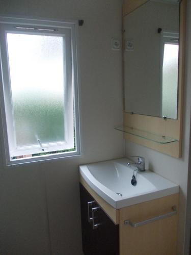 une salle de bain avec un lavabo, un miroir et une fenêtre dans l'établissement Village Vacances 4 etoiles LES MATHES AUX CHARMETTES, aux Mathes