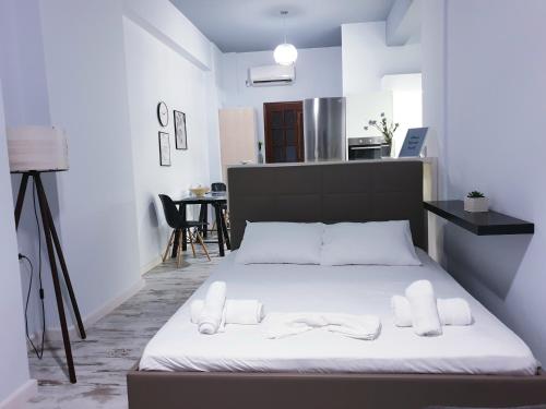 a bedroom with a bed with white sheets and a kitchen at Anastasis garden room in Kalamata
