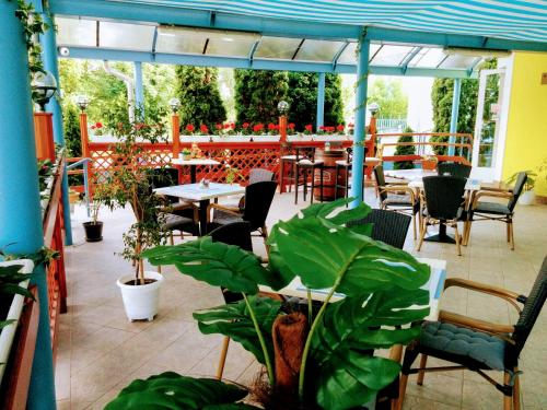 um pátio exterior com mesas, cadeiras e plantas em Boglárka Panzió - Étterem em Mezőkövesd
