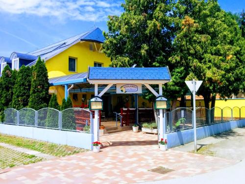 a small yellow building with a blue roof at Boglárka Panzió - Étterem in Mezőkövesd